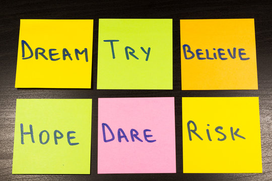 dream try believe hope dare risk sticky note on wooden background
