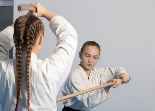 Two girls practice sword on Aikido training on white background