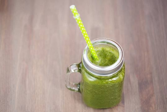A green smoothie in a mason jar with tube