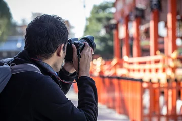 Fototapeten ein Mann, der seine Kamera hält und ein Foto des roten japanischen Tempels oder des Fushimi Inari-Schreins macht © akeeris