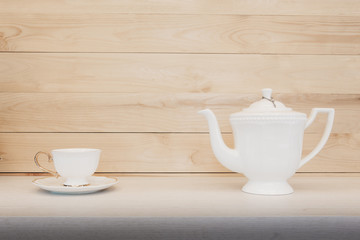 Cup of tea with teapot on wood background.
