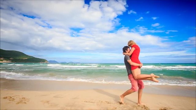 Guy Holds in Arms Circles Kiss Blond Girl on Beach Wave Surf