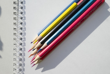 Pile of multicolored pencils on notepad background