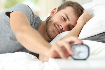 Happy wake up of a happy man stopping alarm clock - obrazy, fototapety, plakaty