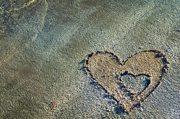 Two hearts drawn on the sand of a beach. Honeymoon or valentine's day greetings on the sand.