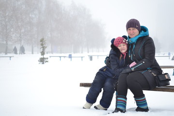 mother and daughter hugging on a bench