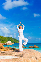 Young woman practices yoga on the rock