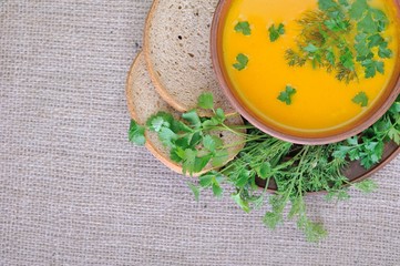Pumpkin Soup; a bowl of pumpkin soup with bundle of greens and slices of bread