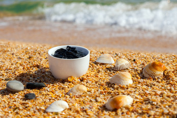Fototapeta na wymiar Dead sea mud for spa treatments in a cup on the beach