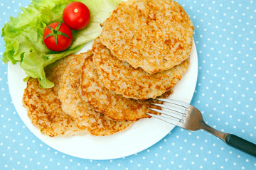 A plate of hash browns with salad and tomatoes