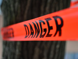 danger sign on red tape/ Danger Red Tape Warning in front of a tree