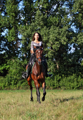 Pretty girl riding in the forest road in summer evening