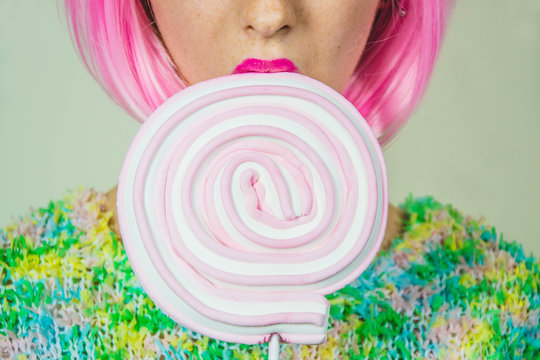 Close up of a part of a girl's face and an ollipop that she's holding - fashion and beuty concept