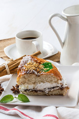 close up of ring-shaped cake with icing sugar, cream, mint, cinn