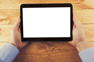 digital tablet with blank screen in hands on the wooden table