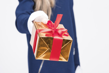 Closeup of Hand of Little Blond Girl Giving Christmas Gift Box Forward