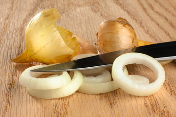 sliced onion and knife on wooden background