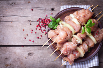 Making kebab  from chicken -  raw meat on skewers on plate