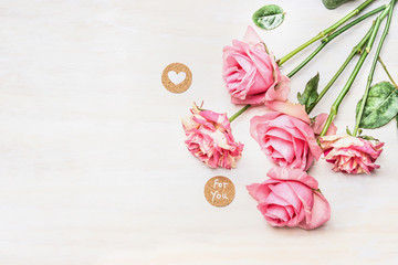 Pink roses and  round sign with message for you and heart on white wooden background, top view,...