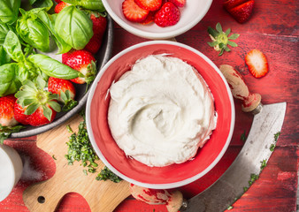 Curd or cream cheese in red bowl with strawberries, close up, top view