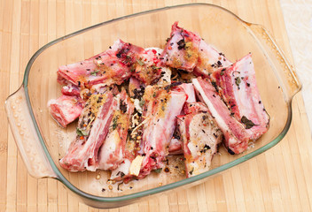 pork ribs with spices in a glass plate on wooden table