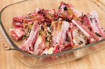 pork ribs with spices in a glass plate on wooden table
