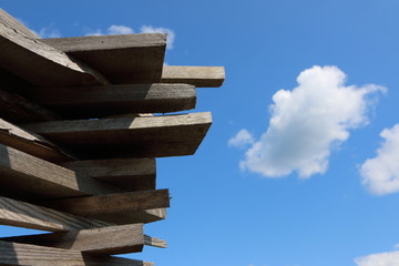 Ends of the rough pine boards in the outdoor stack against a blue sky