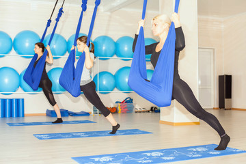 Young women doing aerial yoga exercise