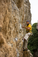 Obraz premium Young male climber hanging on a cliff with a rope.