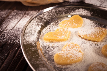cookies in  shape  heart metal plate with flour on a wooden  bac
