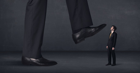 Giant person stepping on a little businessman concept