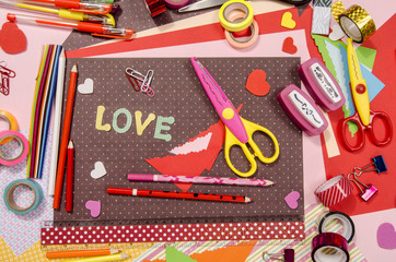 Arts and craft supplies for Saint Valentine's. Color paper, pencils, different washi tapes, craft scissors, hearts supplies for decoration.