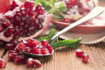 pomegranate and pomegranate seeds in a spoon