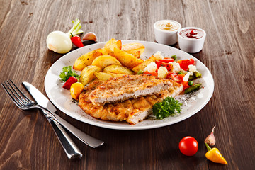 Fried pork chop, baked potatoes and vegetable salad 