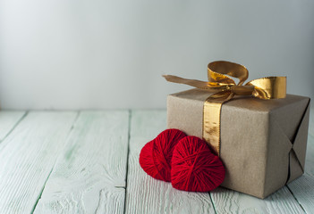 Two knitted hearts, gift box on rustic background