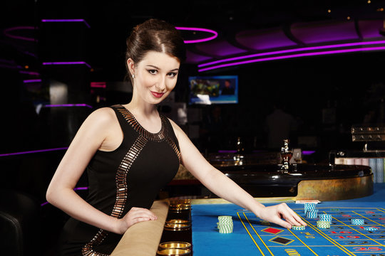 Young nice brunette lady with roulette table in casino