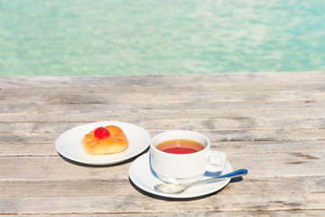 A cup of tea on table with sea at the background