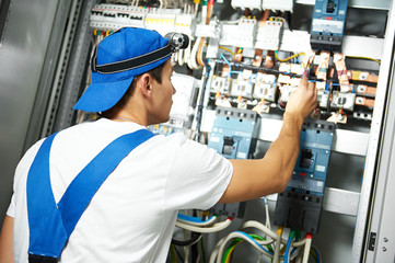 electrician works with electric meter tester in fuse box