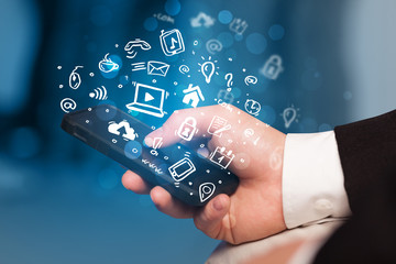 Hand holding smartphone with media icons and symbol