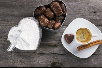 Box of chocolates, cup of coffee on a wooden background. Top vie