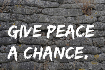 Give peace a chance, text in graffiti style on trench from World War I, relic, fossilized sandbags, background