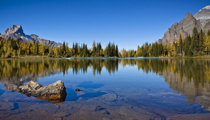 reflections of rugged mountain terrain in a small lake of canada's rocky mountains