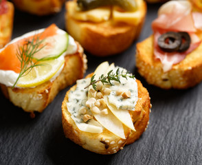 Small canape with grilled baguette with the addition of blue cheese,apple slices, cashew nuts and fresh thyme on black background