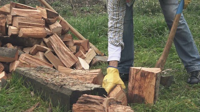 Male lumberjack chopping firewood with axe in backyard