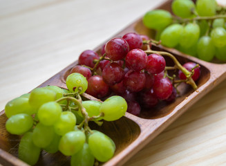 fresh red and green grapes in wooden container