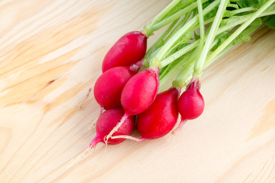 Fresh bunch of radishes, Raphanus sativus, on wooden plate ready to eat or add in healthy salads
