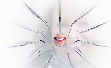 Fototapeta na wymiar Dentist mirror with reflection of woman's teeth and dentist tool