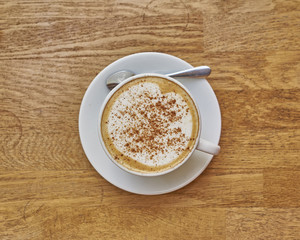 Cappuccino in white cup close-up on wood background