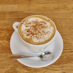 Cappuccino in white cup close-up on wood background