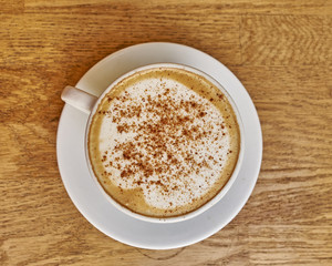 Cappuccino in white cup close-up on wood background